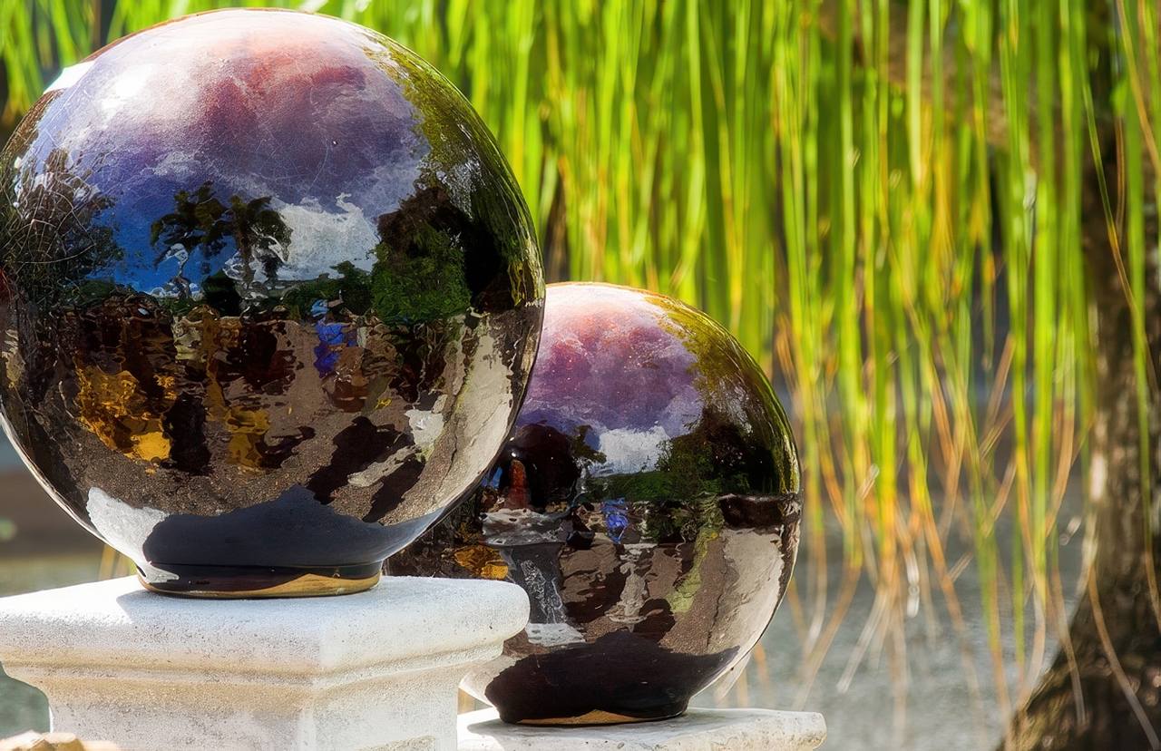 Two shiny decorative garden spheres reflect sunlight and surrounding scenery, potentially intensifying heat onto nearby artificial grass.