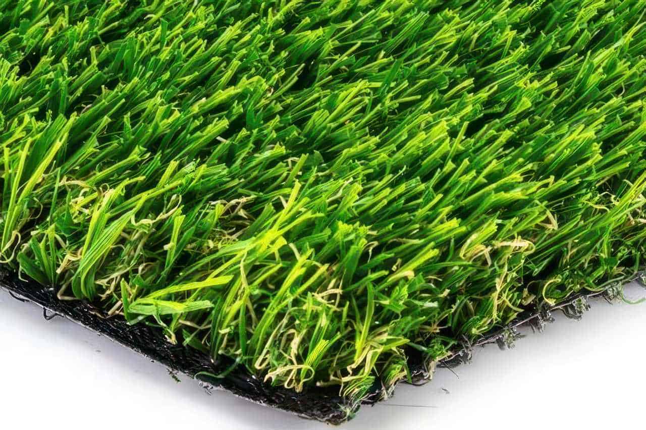 Close-up of artificial turf showing green blades with curled yellow thatch fibers at the base for a natural grass appearance.