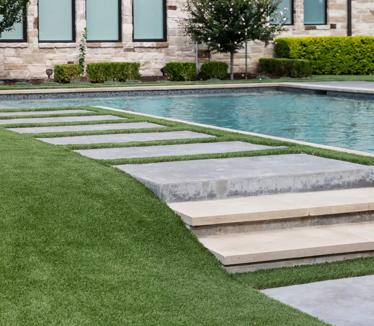 Synthetic Turf Strips between stairs and pavers next to a residential pool