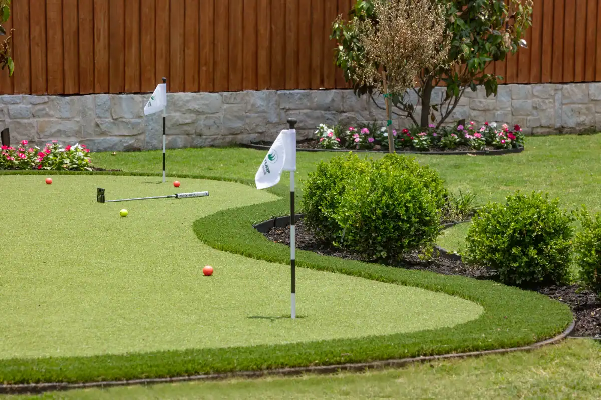 Artificial turf Putting Green in Addison in a residential backyard with flowerbeds