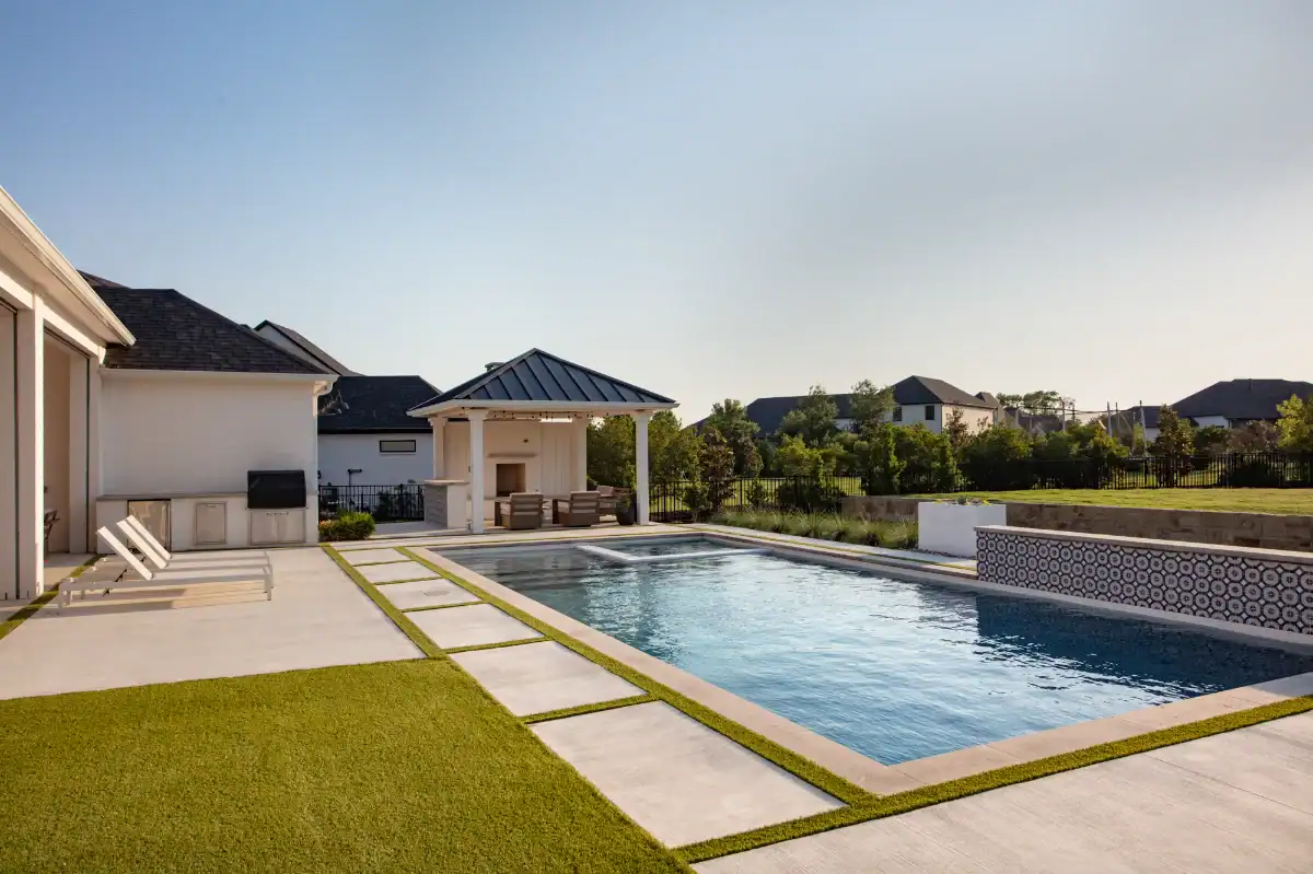 Artificial Grass Strips with large pavers as pool decking in a residential backyard