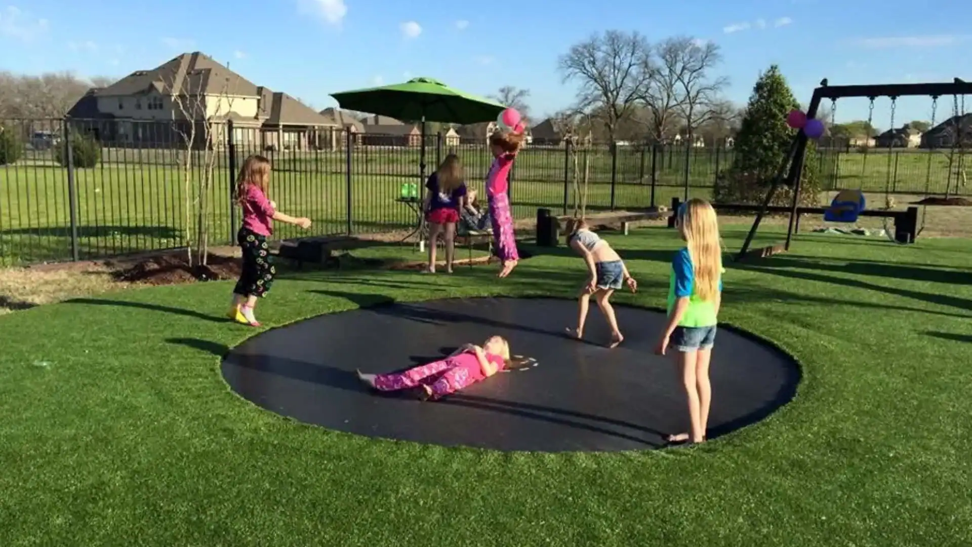 Trampoline with Artificial Turf Kids jumping on an in ground trampoline surrounded by an artificial turf lawn