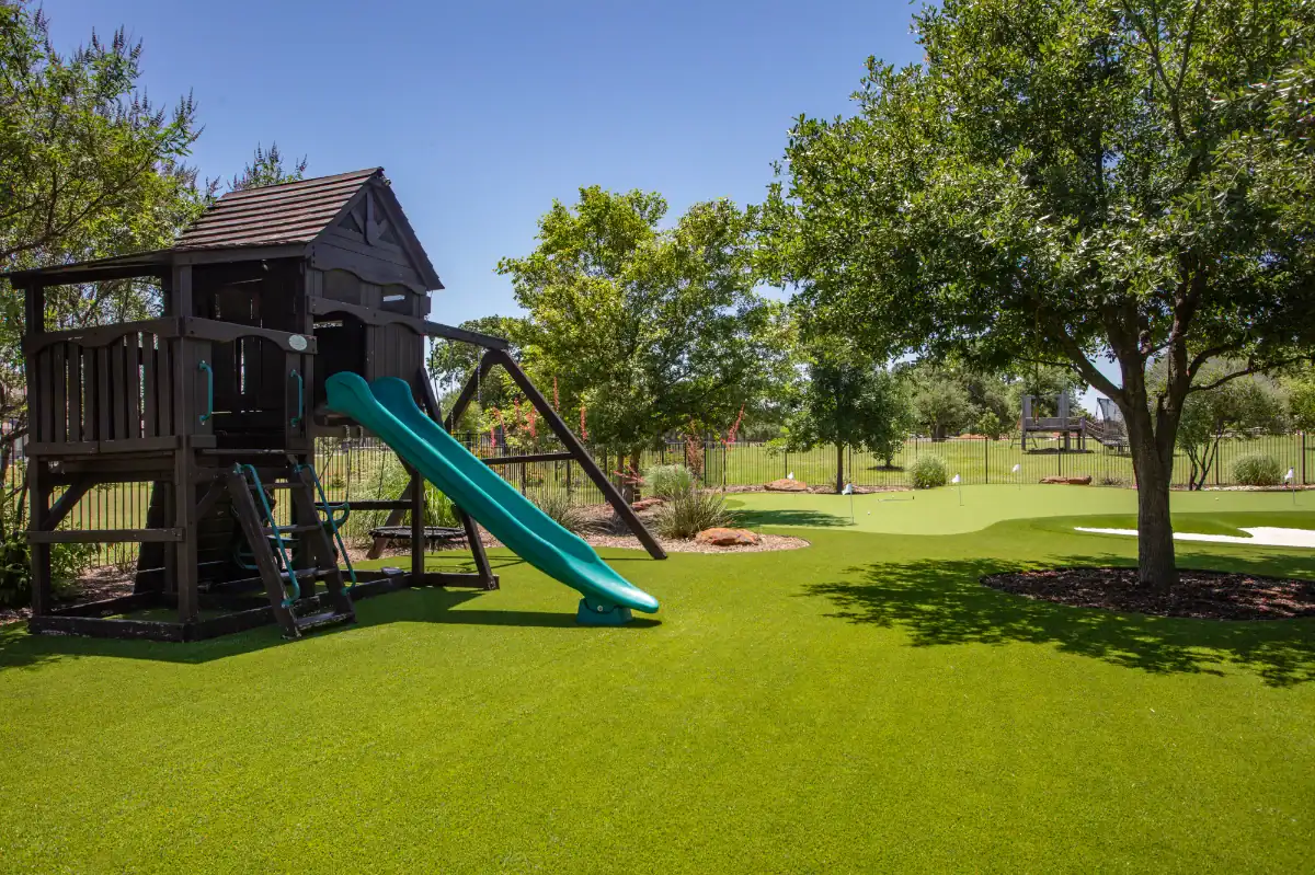 Artificial Grass Play Area Artificial Grass Play Area with a slide and a putting green in a residential backyard