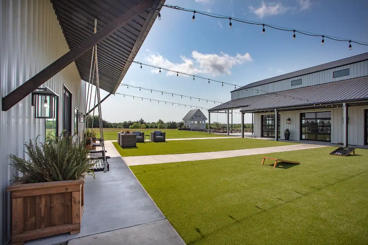 Artificial Turf Wedding Venue in front of a luxury barn with string lights and swings